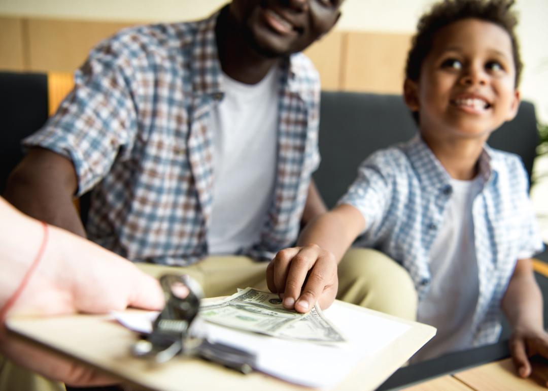 Parent and child using cash to pay bill at restaurant.