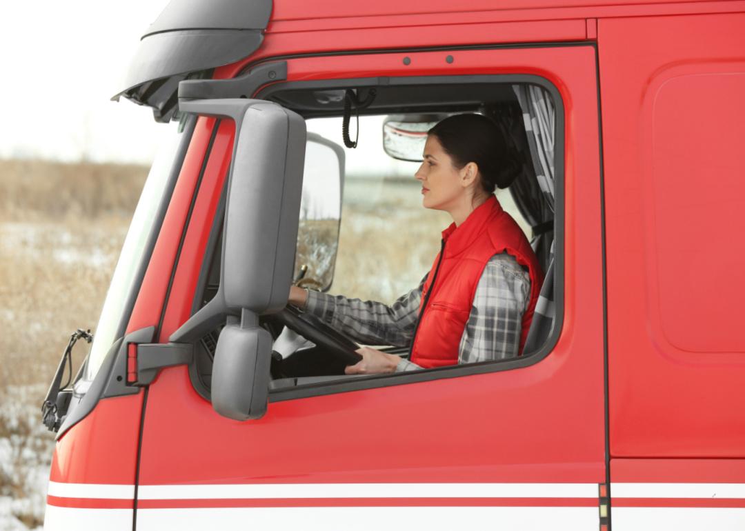 Young woman truck driver sitting and driving large semi truck. 