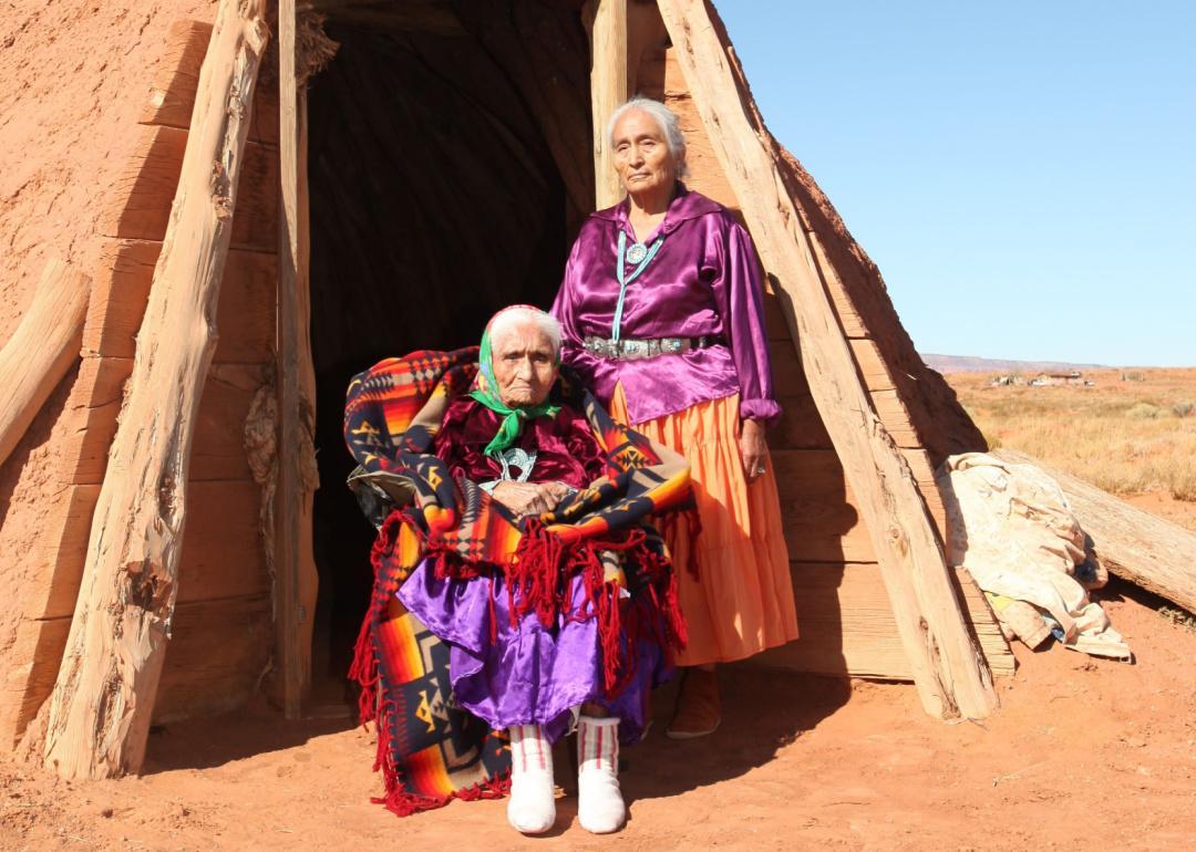 Elderly Navajo people pose outside a tribal home. 