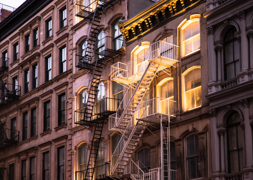 Exterior of a New York City apartment illuminated from within at sunset.