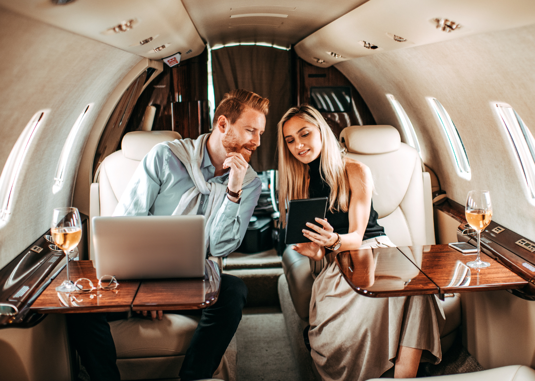 Young rich couple looking at tablet aboard a private jet.