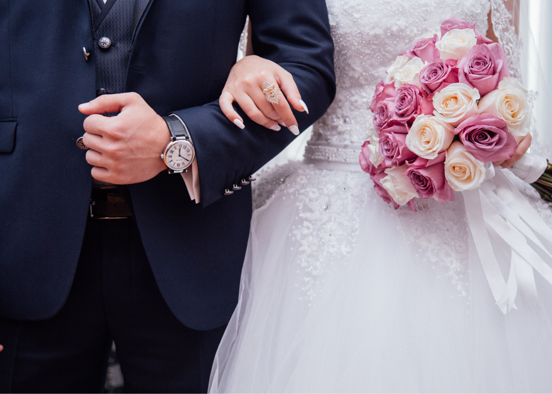 A close up of a bride and groom linking arms.