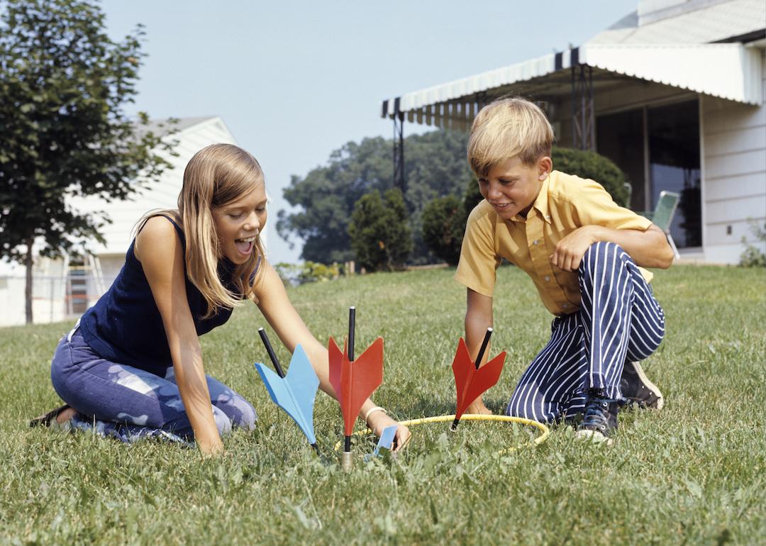 Kids playing with lawn darts in the backyard in the 1970s.