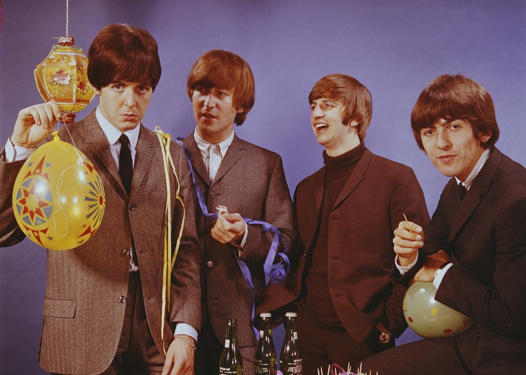 The Beatles pose with bottles of beer and party snacks and balloons in Oct. 1964. From left to right: Paul McCartney, John Lennon, Ringo Starr, and George Harrison.