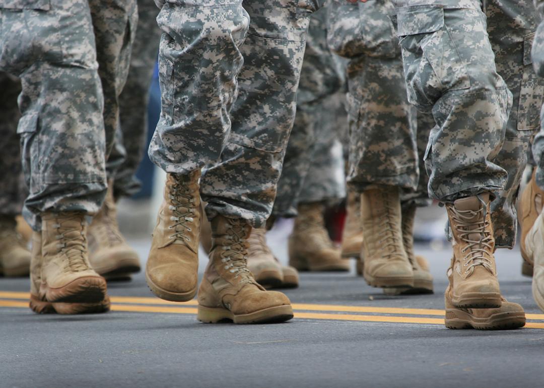 Soldiers wearing camouflage and boots marching in the street, photographed from the ankles down.