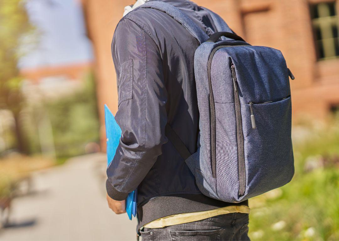 A student walks outside a high school with a backpack.