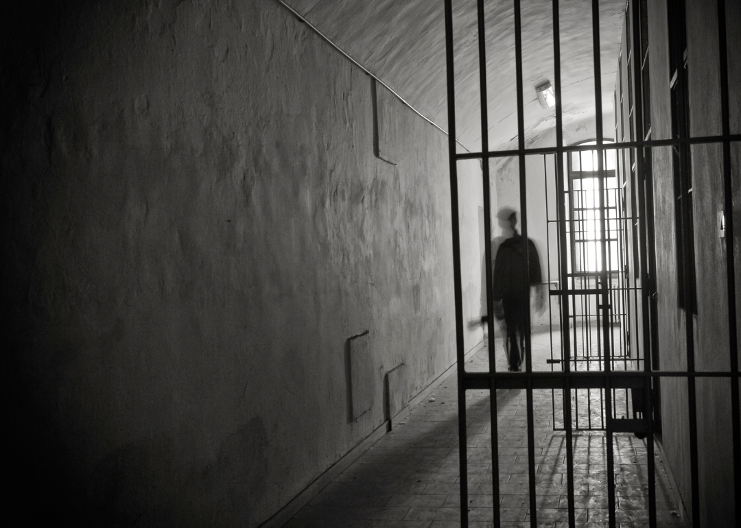 Black and white image of the inside of a prison with a man in shadow.