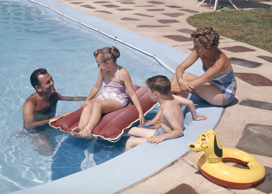 Parents and children hang out in the pool in the summer in the 1950s or '60s.