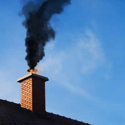 Black smoke coming out of a chimney on a residential home due to fire