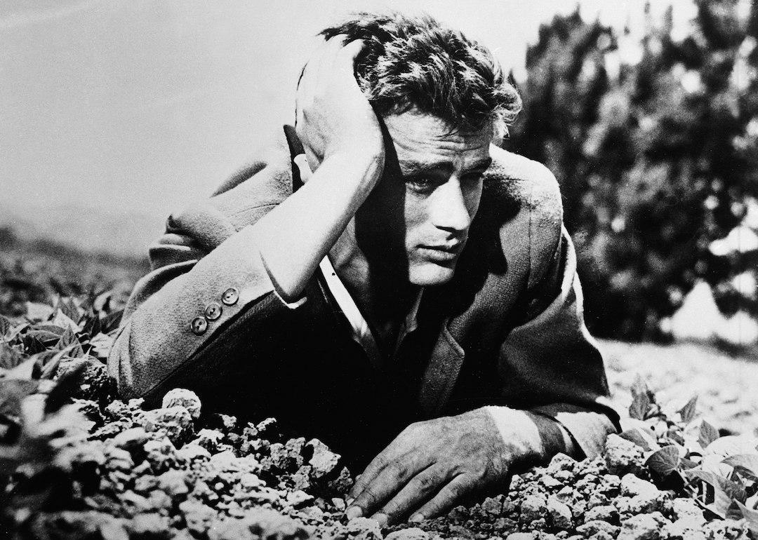 Actor James Dean lies in the dirt with his head leaning on his hand in the 1950s