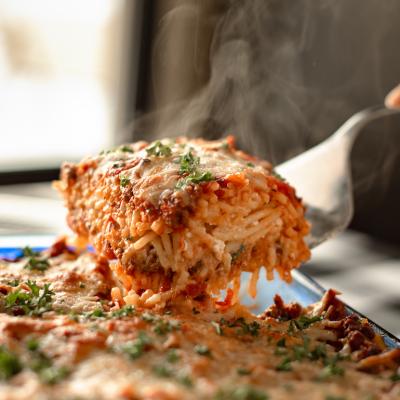 A piece of homemade baked spaghetti being lifted out of pan.