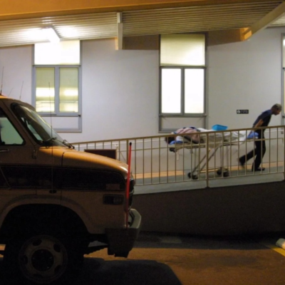 An ambulance driver walks a gurney up a ramp at a hospital