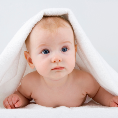 Baby lying on stomach under a white towel