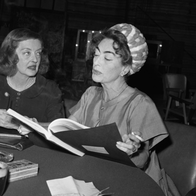  Bette Davis (L), and Joan Crawford are photographed as they look over the script of the film, What Ever Happened to Baby Jane?, in which they will co-star, circa 1962.