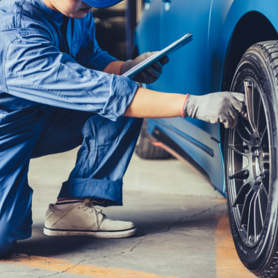 An automotive technician inspecting a vehicle's tires