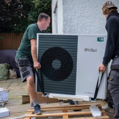 Two men installing a heat pump at a residential home