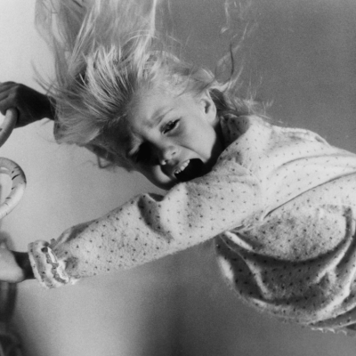 A young Heather O'Rourke holding on to a metal bedframe as she is attempted to be captured by evil spirits in a scene from the film 'Poltergeist', 1982.