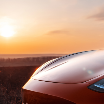 A red Tesla sedan parked in the sunlight