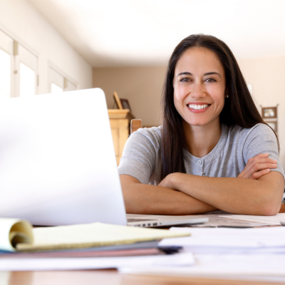 A smiling Latina woman sitting at a desk