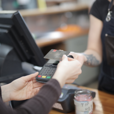 A person pays by credit card at coffee shop register.