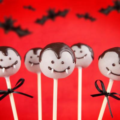 Vampire cake pops on a red background with bats.