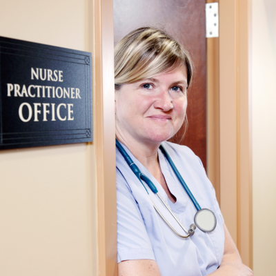 A nurse practitioner stands in the doorway of her office