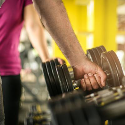 Closeup of hands reaching for weights at gym.