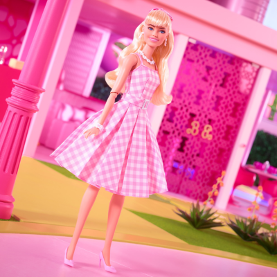 A Barbie doll standing in front of the Dreamhouse