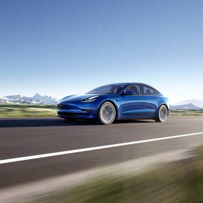 Blue Tesla model 3 driving on road 