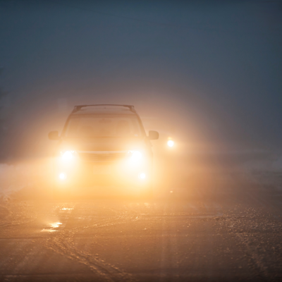 A car driving in foggy conditions with headlights on