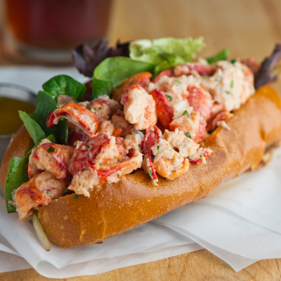 A lobster roll plated with a tub of melted butter on the side