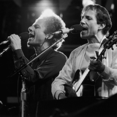  American musicians Art Garfunkel (L) and Paul Simon of the folk duo Simon and Garfunkel perform during a reunion concert at Wembley Stadium, London, England, circa 1982.