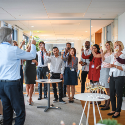 A large group of people in a board room toast a new business opening