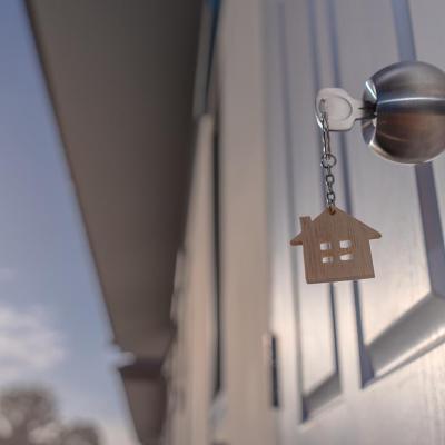 low angle shot of keychain with miniature house figurine hanging from door and the sky visible in the background