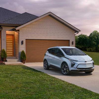 light blue chevy bolt parked in front of a house 