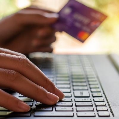 closeup of person using computer keyboard with bank card in hand