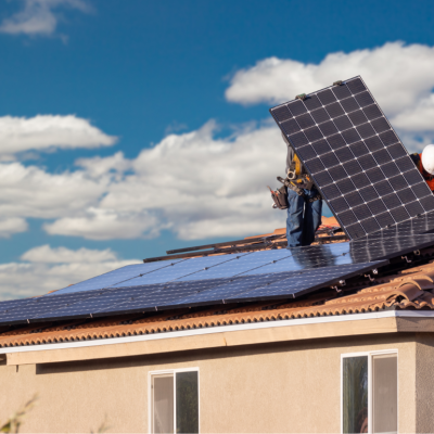 two workers installing solar panels on spanish tile roof house 