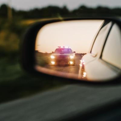 car sideview mirror of police lights approaching