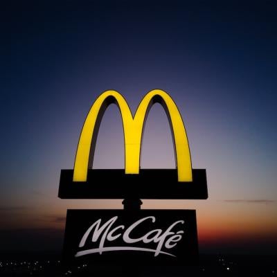 Glowing McDonalds restaurant sign against night sky.