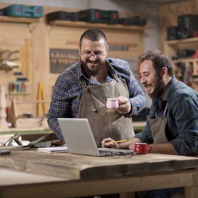 two men in a woodworking shop have a meeting with computer