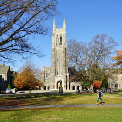 View of the Duke University campus in autumn as a student walks across the lawn.