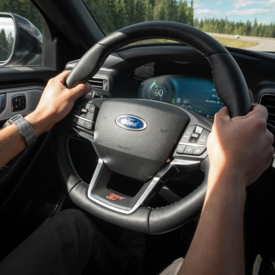 Hands holding the steering wheel of a Ford vehicle