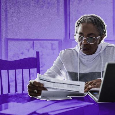 woman looks over bills while background has been shaded purple for dramatic effect