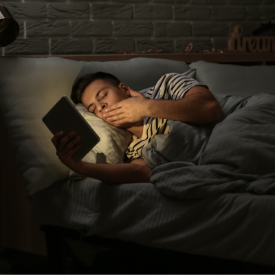 man using ipad in bed with the lights off