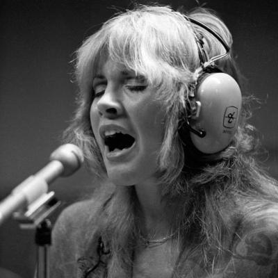 Stevie Nicks singing in the recording studio, wearing headphones.