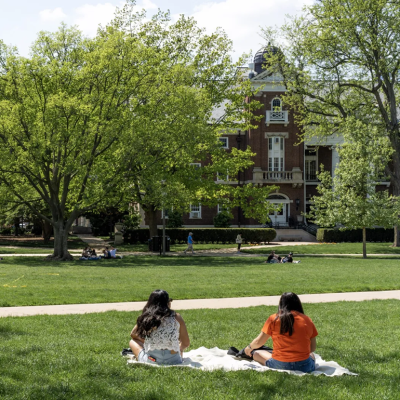 students sitting on the lawn at a college campus