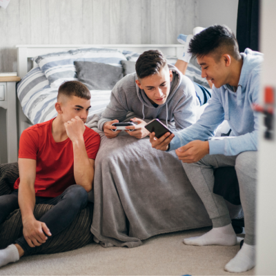 Three teens looking at phones in bedroom