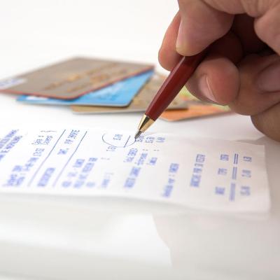 pen in hand circling receipt totals with credit cards in background