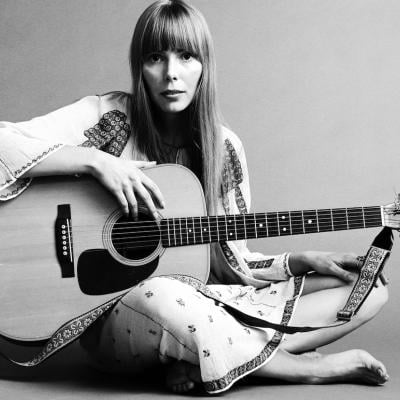 Portrait of musician Joni Mitchell seated on the floor with her acoustic guitar in her lap in 1968.