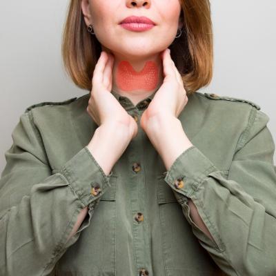 Person in a green shirt checking their thyroid gland.